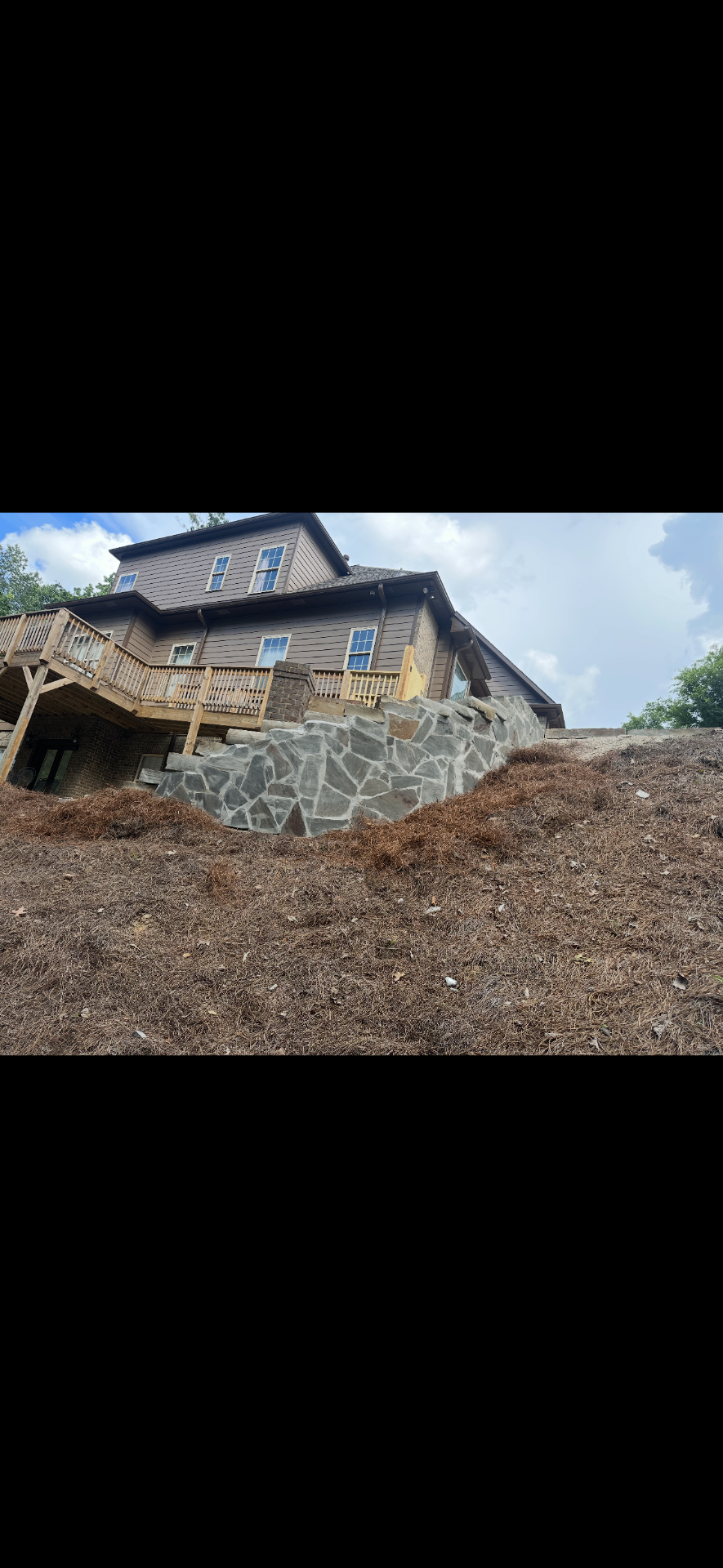 Natural stone retaining wall built into a steep residential slope