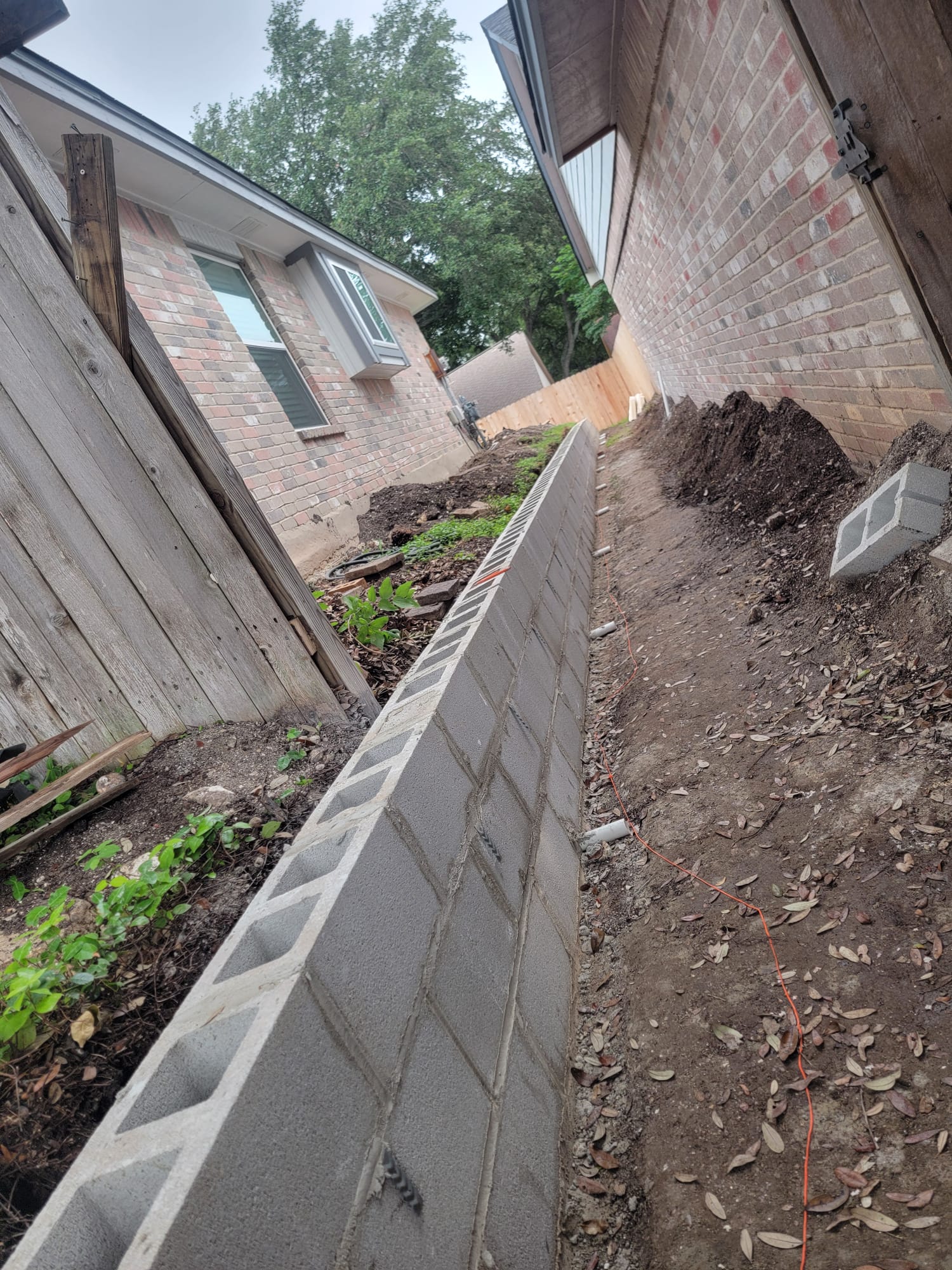 Concrete block retaining wall being built in a narrow side yard