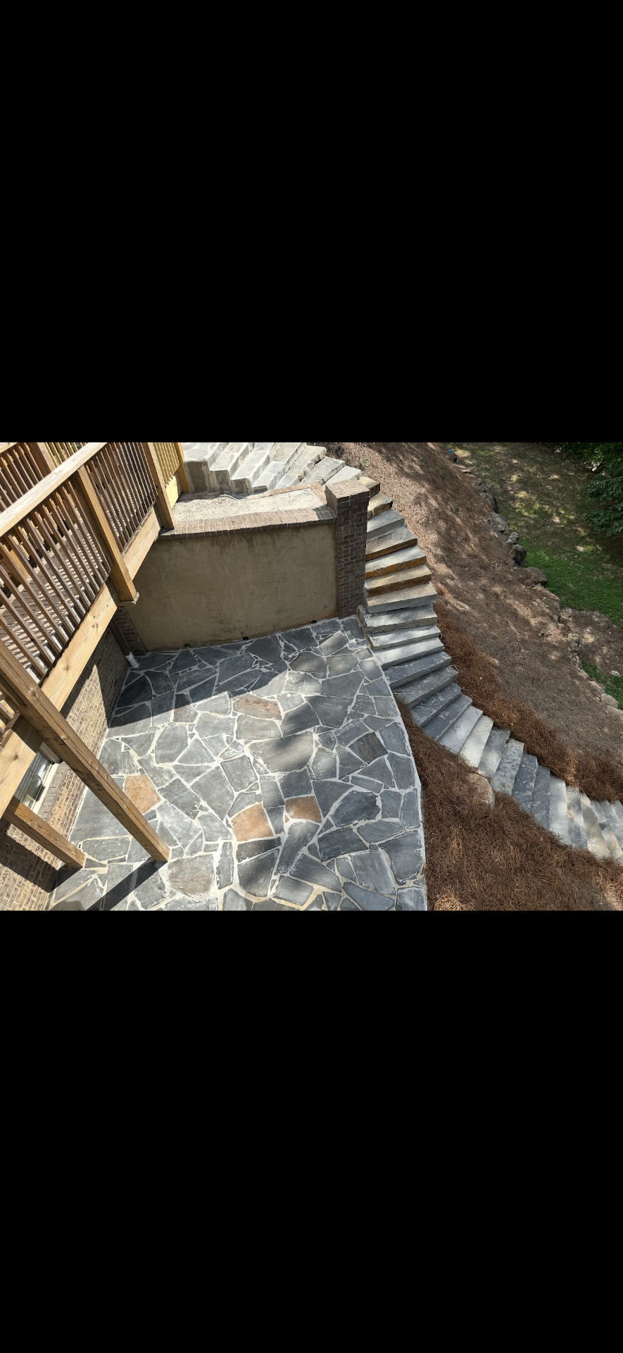 Flagstone patio with long hillside stair run and retaining structure