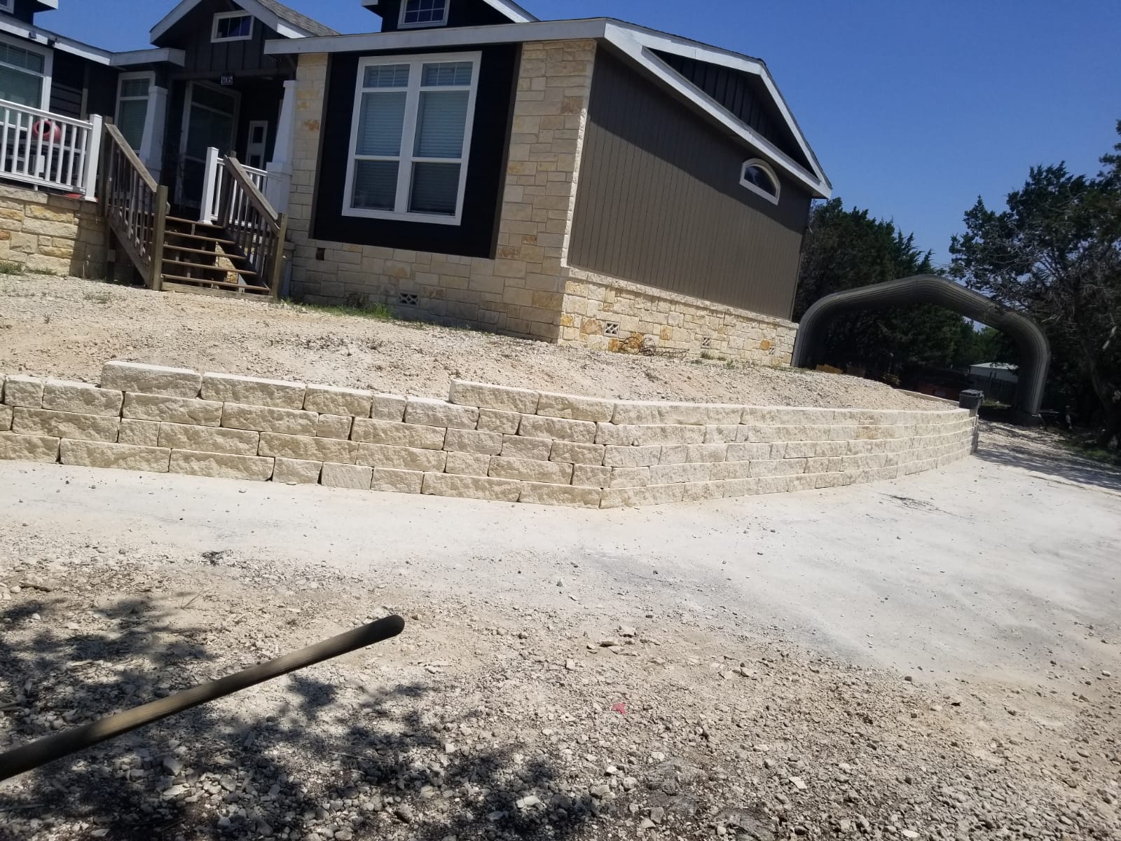 Long limestone retaining wall at the edge of a sloped driveway