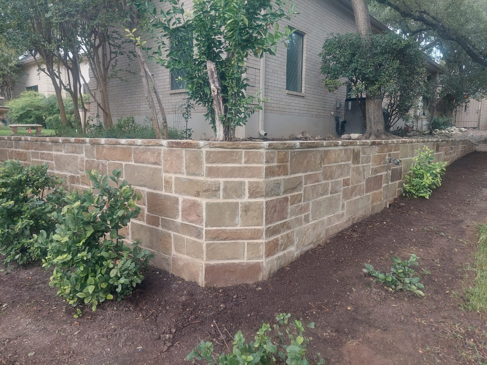 Stone veneer retaining wall surrounding a raised planting bed