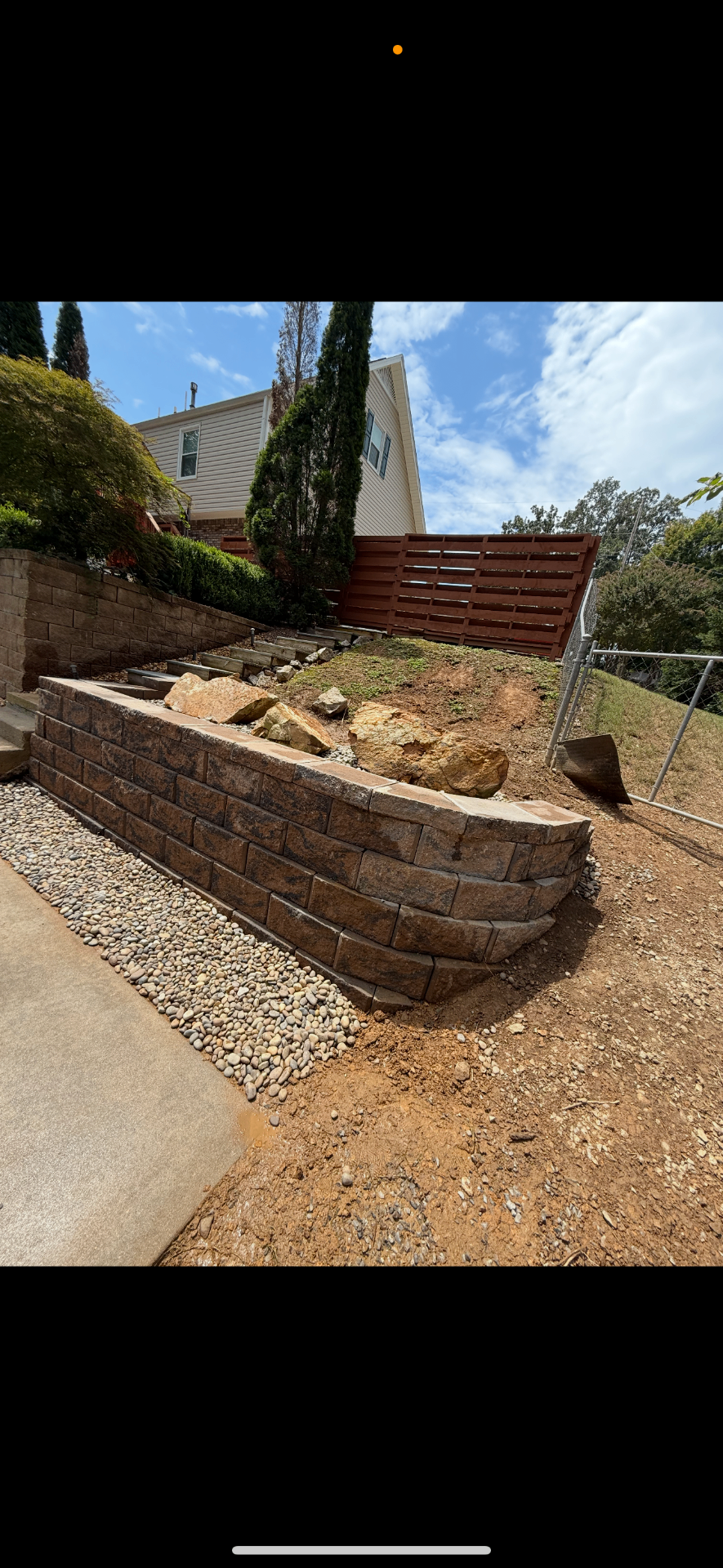 Tiered retaining wall with integrated steps and river rock border